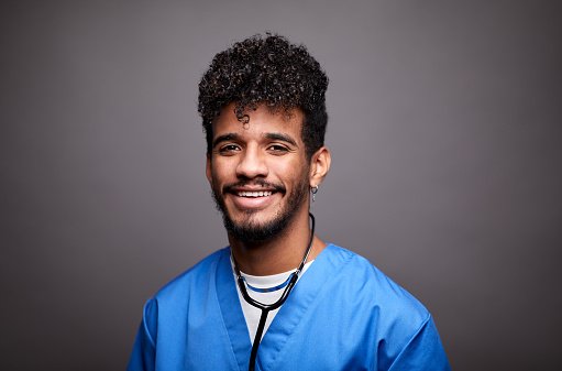 A doctor in blue scrubs with a stethoscope, smiling
