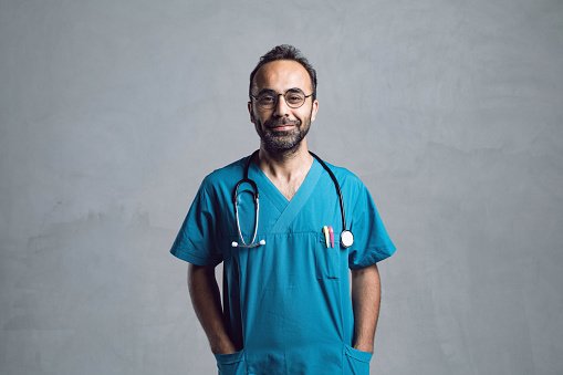 A doctor in teal scrubs with a stethoscope, smiling
