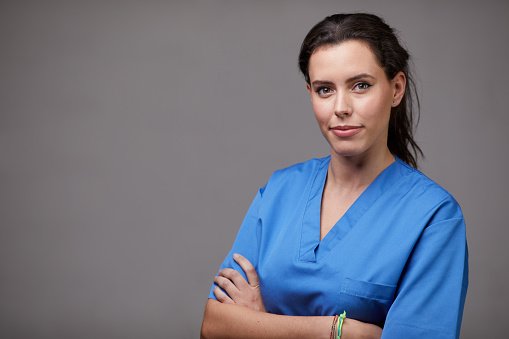 A clinician in blue scrubs with arms crossed