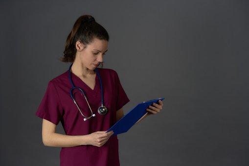 A clinician in maroon scrubs holding a clipboard