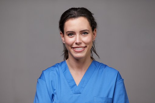 A clinician in blue scrubs, smiling