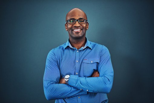 A doctor in a blue shirt with arms crossed