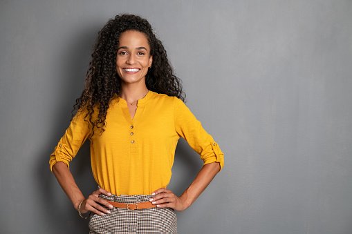 A doctor in a yellow blouse with hands on hips