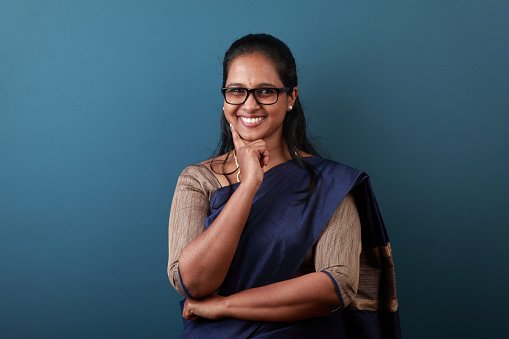 A doctor in a navy outfit with a hand on chin