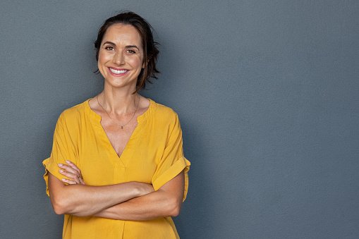 A doctor in a yellow top with arms crossed